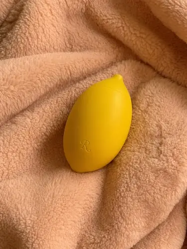 Rumeni klitoralni masažer Lem stranke na mehki rožnati odeji.